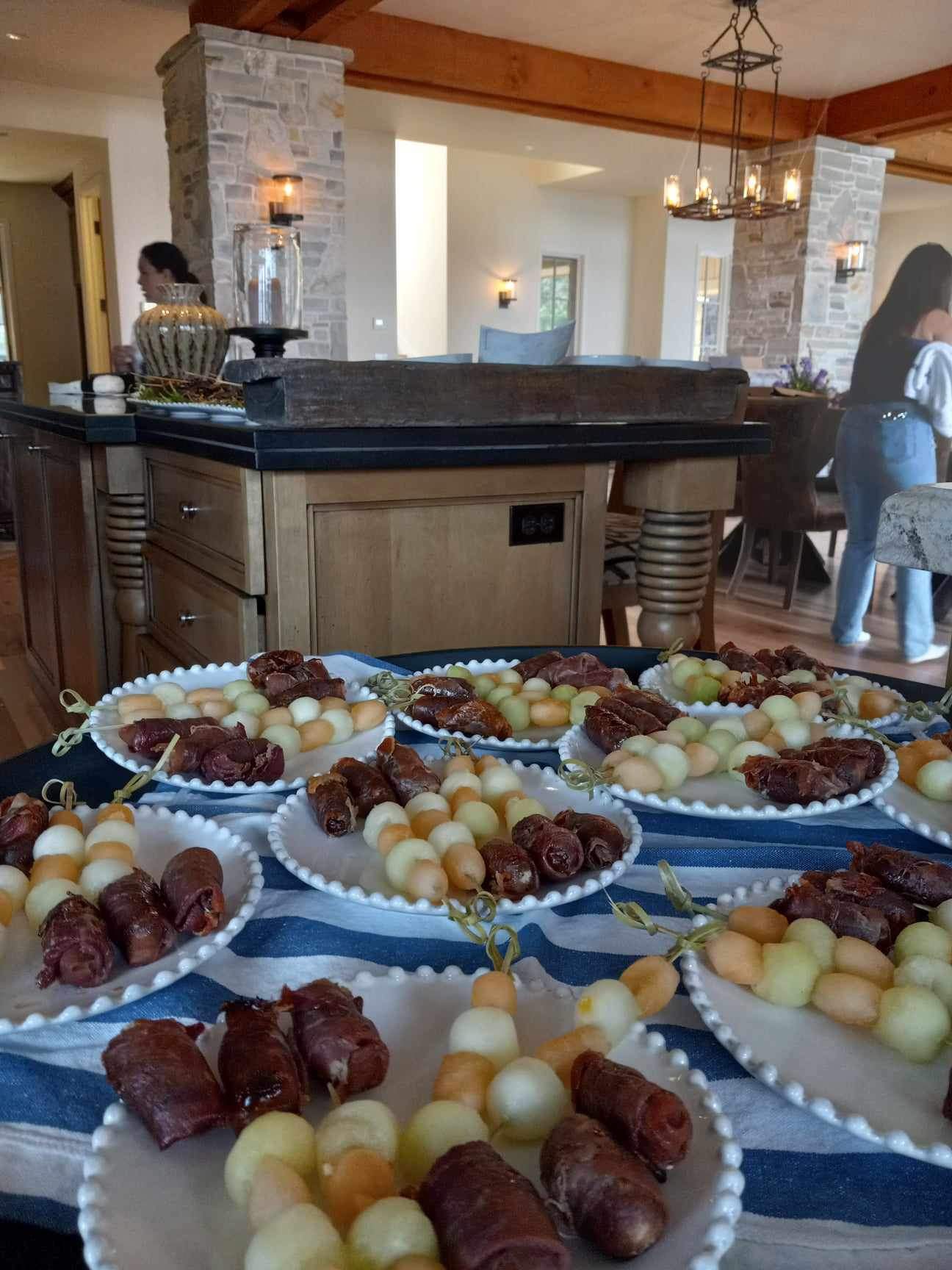 Prosciutto-wrapped dates with melon skewers plated for guests