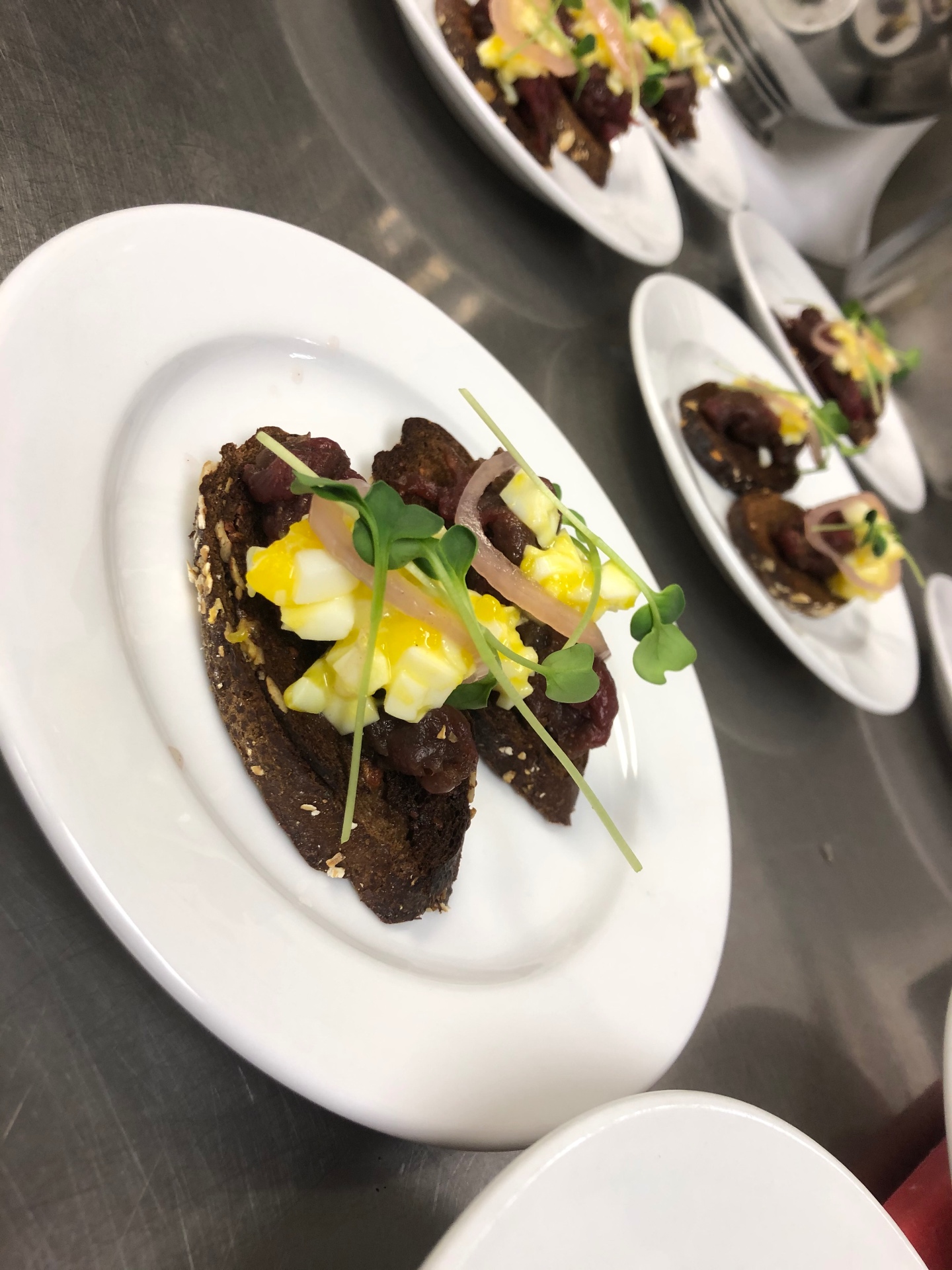 Beef tartare on dark rye toast with egg, pickled shallot, and micro greens