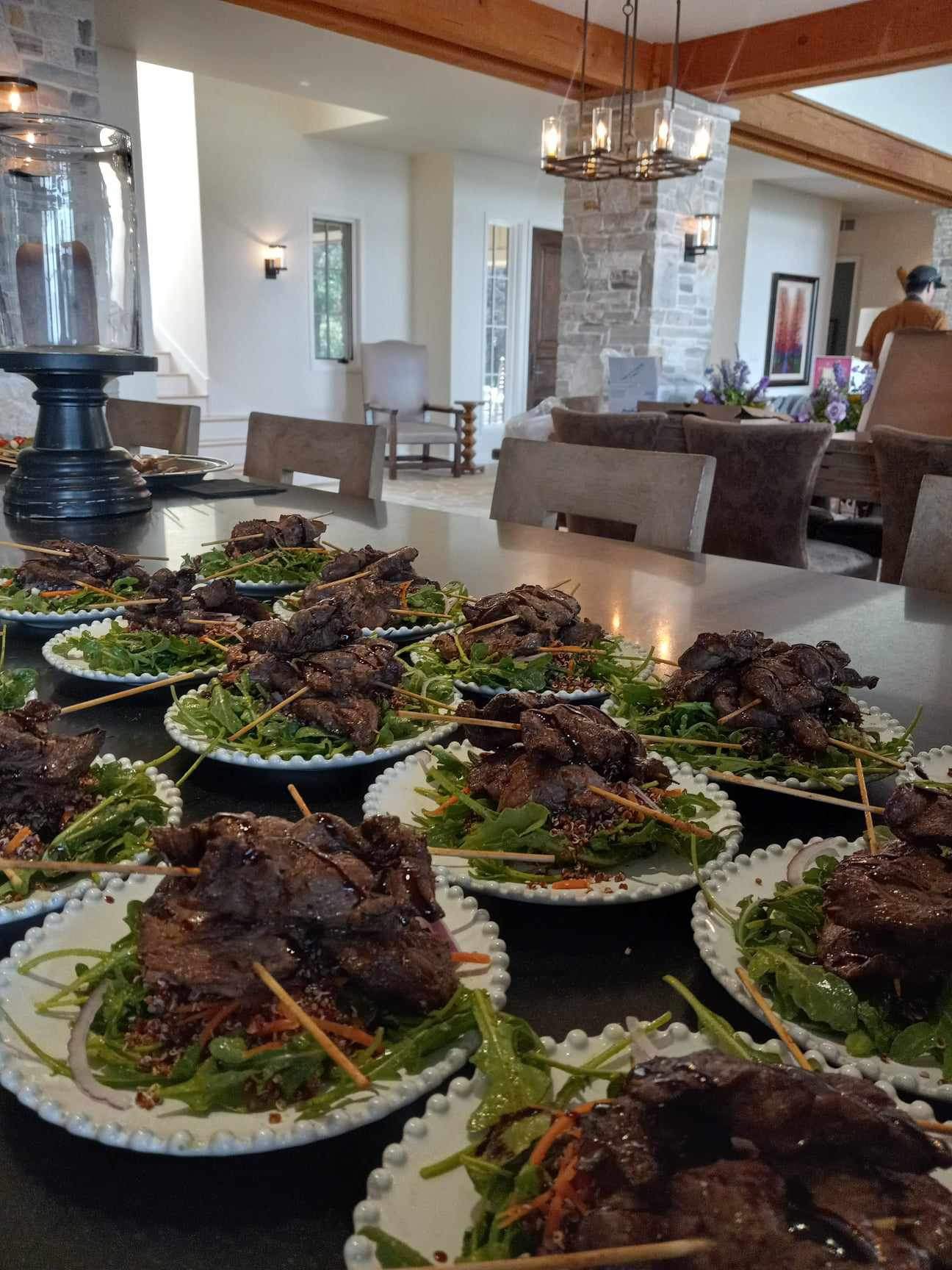 Plated steak skewer salads lined up on a kitchen island in a mountain home
