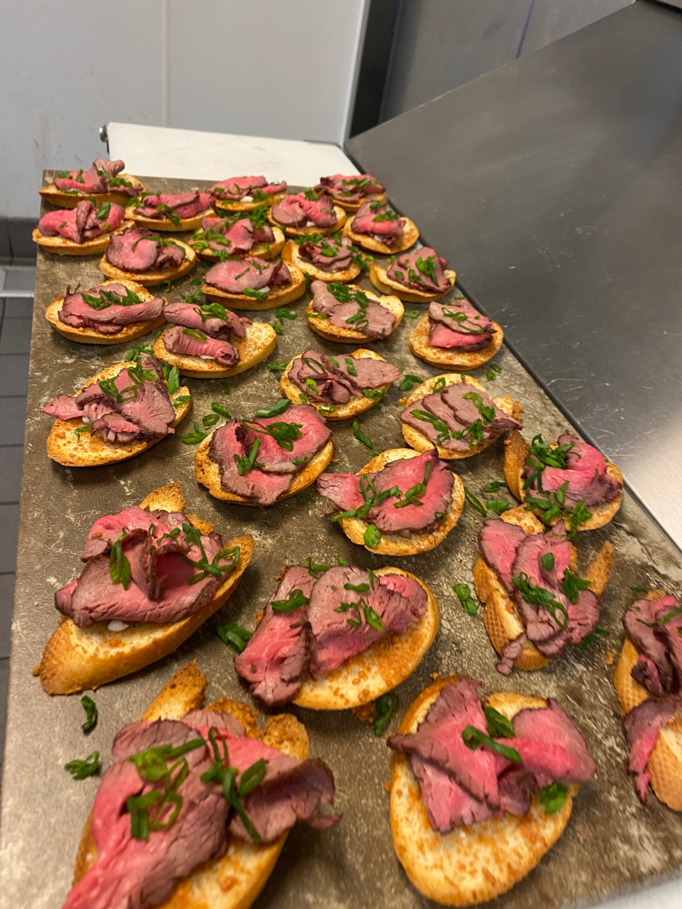 Trays of rare beef tenderloin crostini with horseradish cream and chives