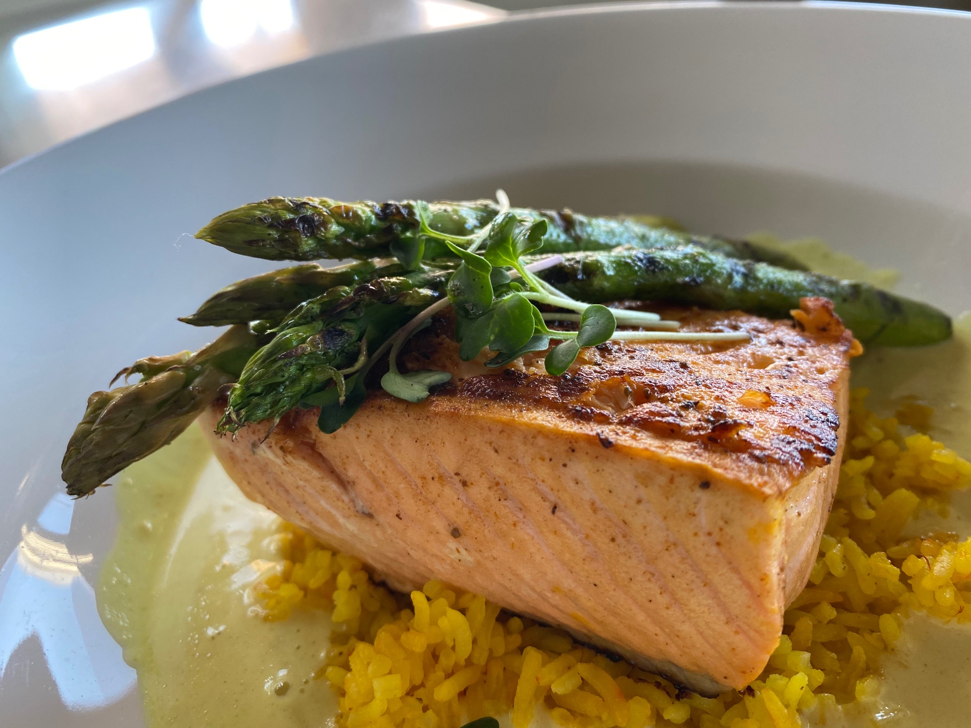 Seared salmon over saffron rice with grilled asparagus and microgreens